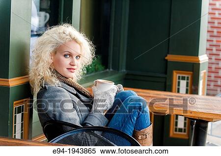 A 22 year old blond woman sitting at an outdoor cafe with a cup of coffee in the winter. View Large Photo Image Stock Photography - A 22 year old blond woman sitting at an outdoor cafe with a cup of coffee in the winter.. Fotosearch