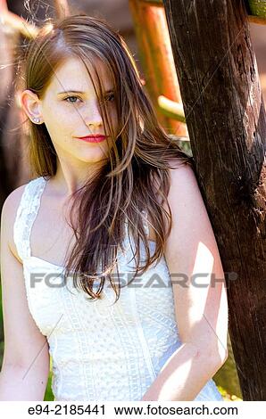 A 22 year old brunette woman looking directly at the camera by a wooden fence on a farm. View Large Photo Image Stock Image - A 22 year old brunette woman looking directly at the camera by a wooden fence on a farm.. Fotosearch