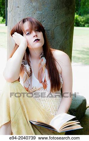 A 22 year old brunette woman sitting on a stone floor holding a book looking at the camera. View Large Photo Image Stock Photo - A 22 year old brunette woman sitting on a stone floor holding a book looking at the camera.. Fotosearch