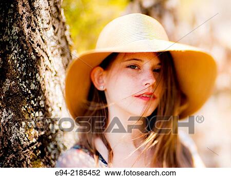 A 22 year old brunette woman wearing a summer dress and a straw hat looking directly at the camera, outdoors. View Large Photo Image Stock Image - A 22 year old brunette woman wearing a summer dress and a straw hat looking directly at the camera, outdoors.. Fotosearch