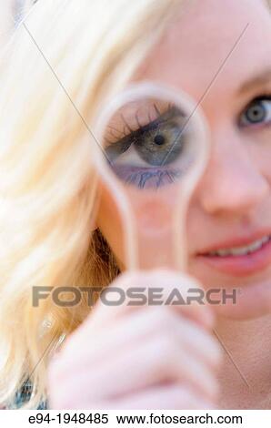 A 23 year old blond woman holding a magnifying glass in front of her face causing distortion of her eyes. View Large Photo Image Stock Photography - A 23 year old blond woman holding a magnifying glass in front of her face causing distortion of her eyes.. Fotosearch