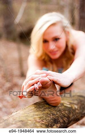 Picture - A 23 year old blond woman in work out clothing stretching in a forest setting.. Fotosearch