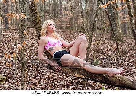 A 23 year old blond woman in work out clothing reclining on a tree branch in a forest setting. View Large Photo Image Stock Photograph - A 23 year old blond woman in work out clothing reclining on a tree branch in a forest setting.. Fotosearch