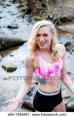 A 23 year old blond woman wearing a pink sports bra outside smiling at the camera. View Large Photo Image Stock Image - A 23 year old blond woman wearing a pink sports bra outside smiling at the camera.. Fotosearch