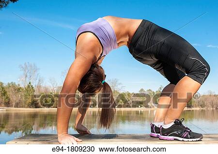 A 23 year old brunette woman in workout clothing doing a back bend on a bench by a pond View Large Photo Image Stock Image - A 23 year old brunette woman in workout clothing doing a back bend on a bench by a pond. Fotosearch