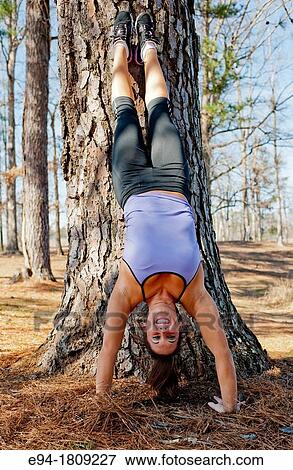A 23 year old brunette woman in workout clothing doing a handstand against a tree outdoors View Large Photo Image Stock Photo - A 23 year old brunette woman in workout clothing doing a handstand against a tree outdoors. Fotosearch
