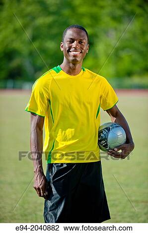 A 24 year old black man wearing soccer clothing holding a soccer ball smiling at the camera. View Large Photo Image Stock Image - A 24 year old black man wearing soccer clothing holding a soccer ball smiling at the camera.. Fotosearch
