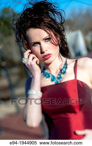 Stock Photography - A 24 year old brunette woman in a fancy red dress and high heels on a sunny day outdoors.. Fotosearch