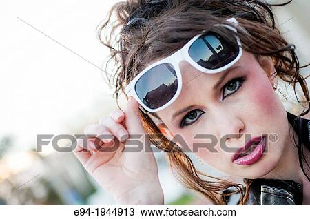 Stock Image - A 24 year old brunette woman in with white rimmed sunglasses.. Fotosearch