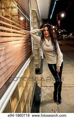 A 24 year old brunette woman looking at the camera wearing a sweater, black boots and black tights standing on a sidewalk by a store front in a run-down urban setting View Large Photo Image Stock Photo - A 24 year old brunette woman looking at the camera wearing a sweater, black boots and black tights standing on a sidewalk by a store front in a run-down urban setting. Fotosearch
