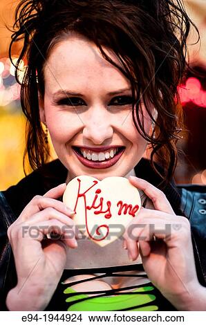 Picture - A 24 year old brunette woman smiling at the camera holding a cookie.. Fotosearch