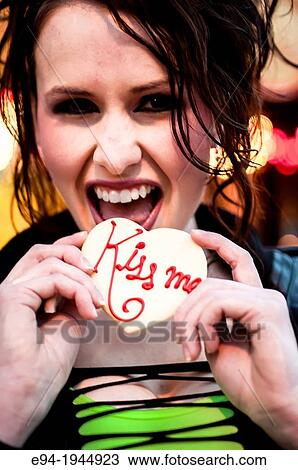Stock Image - A 24 year old brunette woman smiling at the camera holding a cookie.. Fotosearch