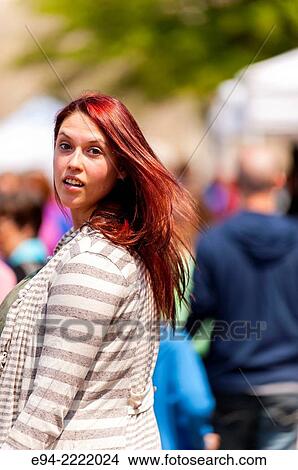 Picture - A 24 year old brunette woman smiling over her shoulder in an outdoor market.. Fotosearch