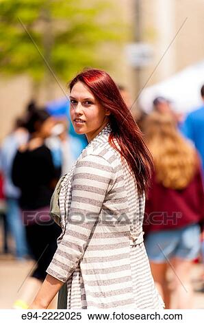 Stock Photography - A 24 year old brunette woman smiling over her shoulder in an outdoor market.. Fotosearch