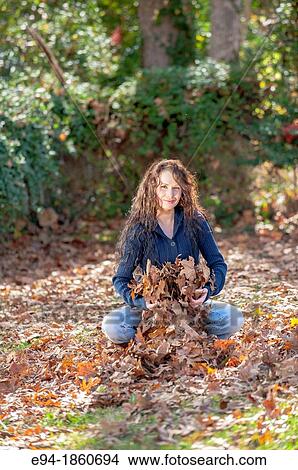A 24 year old brunette woman throwing leaves in a back yard in the fall View Large Photo Image Picture - A 24 year old brunette woman throwing leaves in a back yard in the fall. Fotosearch