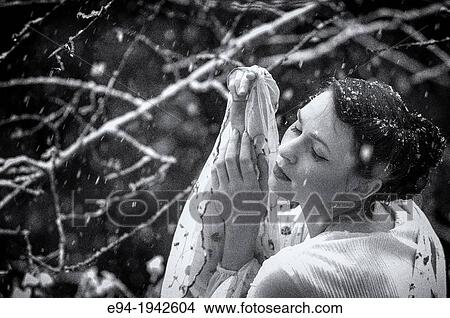 A 24 year old woman wearing a white dress standing in a garden during a snow storm. View Large Photo Image Picture - A 24 year old woman wearing a white dress standing in a garden during a snow storm.. Fotosearch