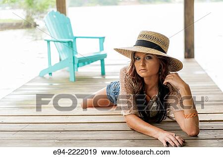 A 27 year old brunette woman wearing a straw hat lying on a boat dock looking at the camera, outdoors. View Large Photo Image Stock Photo - A 27 year old brunette woman wearing a straw hat lying on a boat dock looking at the camera, outdoors.. Fotosearch