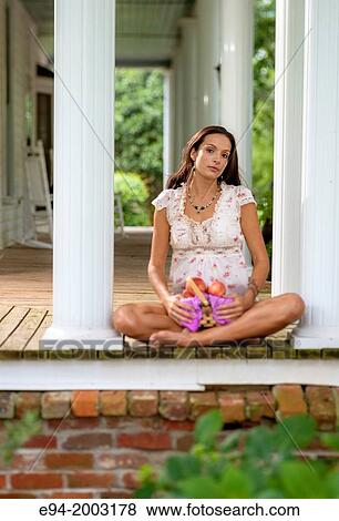 A 27 year old brunette woman wearing cut off shorts sitting on a porch holding a basket of peaches. View Large Photo Image Stock Photo - A 27 year old brunette woman wearing cut off shorts sitting on a porch holding a basket of peaches.. Fotosearch