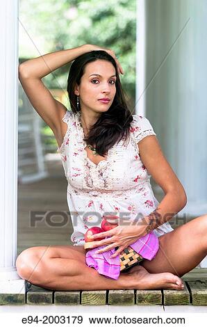 A 27 year old brunette woman wearing cut off shorts sitting on a porch holding a basket of peaches. View Large Photo Image Stock Photo - A 27 year old brunette woman wearing cut off shorts sitting on a porch holding a basket of peaches.. Fotosearch