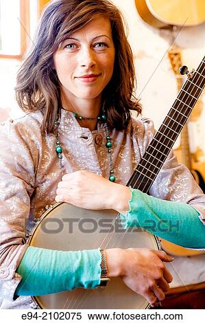A 28 year old brunette woman holding a banjo on her lap with grinning at the camera. View Large Photo Image Stock Photography - A 28 year old brunette woman holding a banjo on her lap with grinning at the camera.. Fotosearch
