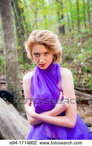 Stock Image - A 29 year old blond woman in a forest wrapped in a purple cloth. Fotosearch