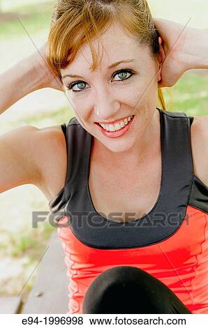 A 31 year old red headed women in work out clothing exercising on a table in a park setting. View Large Photo Image Stock Photo - A 31 year old red headed women in work out clothing exercising on a table in a park setting.. Fotosearch