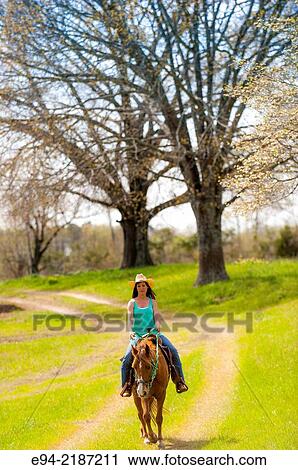 A 36 year old brunette woman wearing jeans and a straw hat riding a horse on a farm. View Large Photo Image Stock Image - A 36 year old brunette woman wearing jeans and a straw hat riding a horse on a farm.. Fotosearch