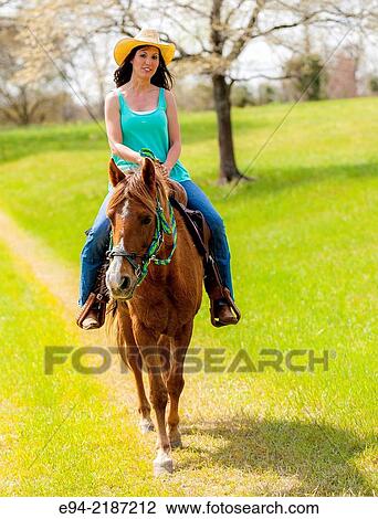 A 36 year old brunette woman wearing jeans and a straw hat riding a horse on a farm. View Large Photo Image Stock Image - A 36 year old brunette woman wearing jeans and a straw hat riding a horse on a farm.. Fotosearch