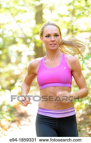 A 38 year old blond woman wearing work-out clothing jogging on a trail in a forest setting in the fall View Large Photo Image Stock Image - A 38 year old blond woman wearing work-out clothing jogging on a trail in a forest setting in the fall. Fotosearch