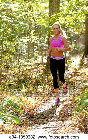 A 38 year old blond woman wearing work-out clothing jogging on a trail in a forest setting in the fall View Large Photo Image Stock Image - A 38 year old blond woman wearing work-out clothing jogging on a trail in a forest setting in the fall. Fotosearch