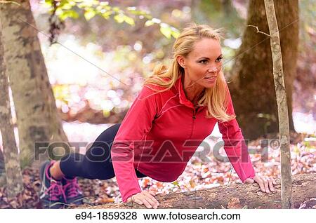 A 38 year old blond woman wearing work-out clothing doing a push-up on a log in a forest setting in the fall View Large Photo Image Stock Photo - A 38 year old blond woman wearing work-out clothing doing a push-up on a log in a forest setting in the fall. Fotosearch