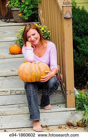 Stock Image - A 38 year old redheaded woman in a garden setting with pumpkins. Fotosearch