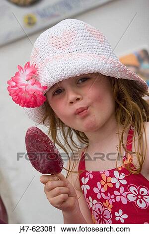 Stock Image - A 4 year old girl licking a lolly, pulling face because its cold.. Fotosearch