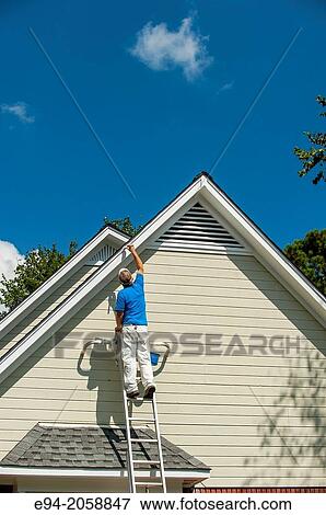 A 45 year old man on a ladder painting the white trim of a house. View Large Photo Image Stock Photo - A 45 year old man on a ladder painting the white trim of a house.. Fotosearch