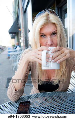 A 48 year old blond woman in casual clothing at an outdoor cafe holding a coffee cup View Large Photo Image Stock Image - A 48 year old blond woman in casual clothing at an outdoor cafe holding a coffee cup. Fotosearch
