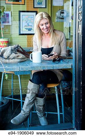 A 48 year old blond woman in casual clothing relaxing in a coffee shop seen through the window View Large Photo Image Stock Photo - A 48 year old blond woman in casual clothing relaxing in a coffee shop seen through the window. Fotosearch