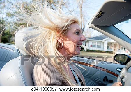 A 48 year old blond woman talking and being expressive while driving her convertible car View Large Photo Image Stock Photo - A 48 year old blond woman talking and being expressive while driving her convertible car. Fotosearch