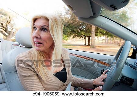 A 48 year old blond woman talking and being expressive while driving her convertible car View Large Photo Image Stock Photo - A 48 year old blond woman talking and being expressive while driving her convertible car. Fotosearch