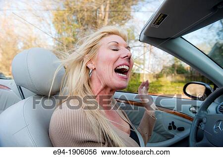 A 48 year old blond woman talking and being expressive while driving her convertible car View Large Photo Image Stock Photograph - A 48 year old blond woman talking and being expressive while driving her convertible car. Fotosearch