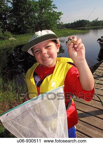 Stock Image - a 5 or 6 year old boy with a frog that he caught in a dip net at a lake. Fotosearch