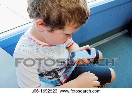 a 5 year old boy using an IPod or IPhone or cell phone View Large Photo Image Stock Image - a 5 year old boy using an IPod or IPhone or cell phone. Fotosearch