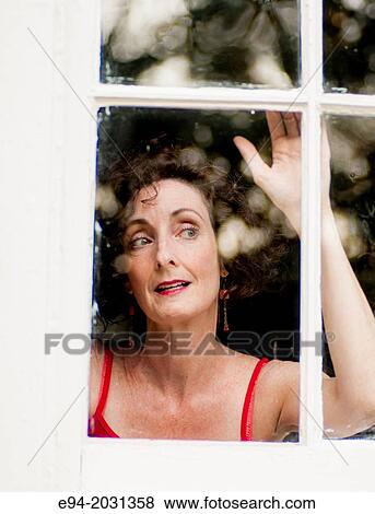 Stock Photo - A 51 year old brunette woman looking out of a window.. Fotosearch