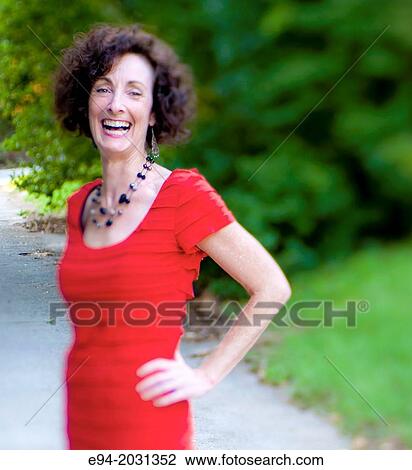 A 51 year old brunette woman wearing a red dress standing on a country road. View Large Photo Image Stock Image - A 51 year old brunette woman wearing a red dress standing on a country road.. Fotosearch