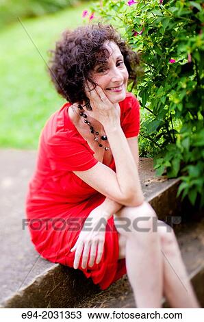 A 51 year old brunette woman wearing a red dress sitting on steps in her front yard. View Large Photo Image Stock Image - A 51 year old brunette woman wearing a red dress sitting on steps in her front yard.. Fotosearch