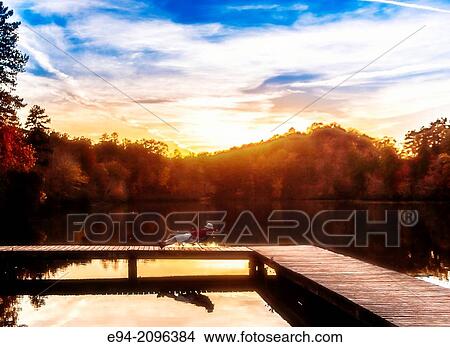 A 53 year old man lounging on a folding chair on a wooden dock by a lake with fall foliage in the background. Oak Mountain State Park, Alabama. View Large Photo Image Picture - A 53 year old man lounging on a folding chair on a wooden dock by a lake with fall foliage in the background. Oak Mountain State Park, Alabama.. Fotosearch