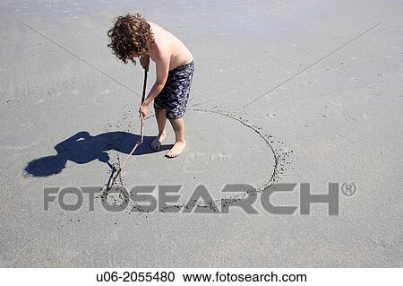 A 7 year old boy in a swim suit at the beach drawing a circle in the sand with a stick to signify the earth our planet View Large Photo Image Stock Image - A 7 year old boy in a swim suit at the beach drawing a circle in the sand with a stick to signify the earth our planet. Fotosearch