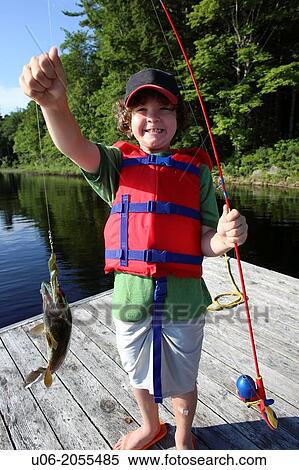 A 7 year old boy standing on a wharf holding a fishing rod and a fish that he caught View Large Photo Image Stock Photography - A 7 year old boy standing on a wharf holding a fishing rod and a fish that he caught. Fotosearch