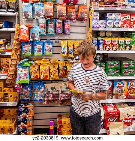 A 9 year old boy choosing a treat for his dog while shopping in a supermarket in the Uk. View Large Photo Image Stock Photo - A 9 year old boy choosing a treat for his dog while shopping in a supermarket in the Uk.. Fotosearch