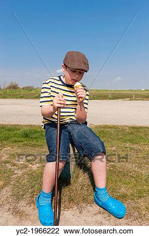 Stock Image - A 9 year old boy eating an ice cream in Walberswick, Suffolk, England, Britain, Uk.. Fotosearch