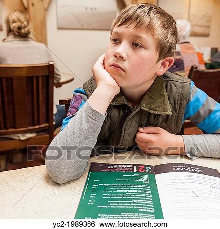 Stock Photograph - A 9 year old boy looks at the menu in Byfords cafe in Holt, Norfolk, England, Britain, Uk.. Fotosearch